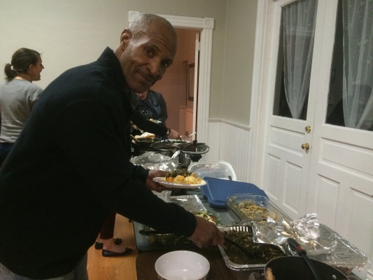 Michael Rodney-Bey scoops up some of the collard greens and turkey he cooked for the Back on My Feet holiday potluck.