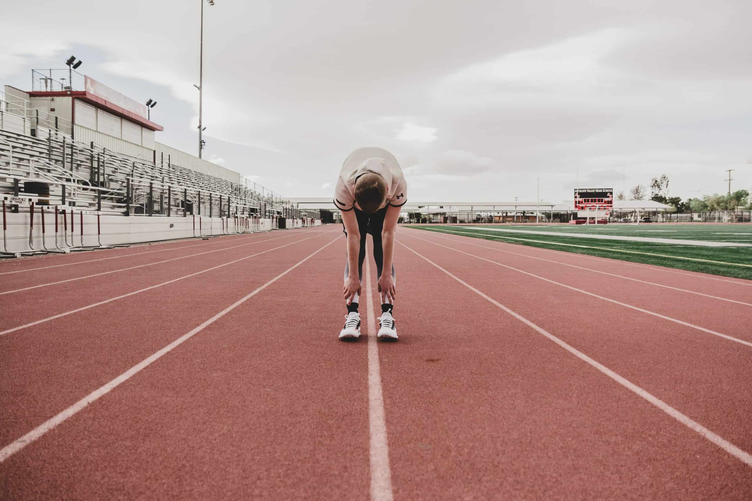 A runner mid-track workout, folded over in exhaustion.