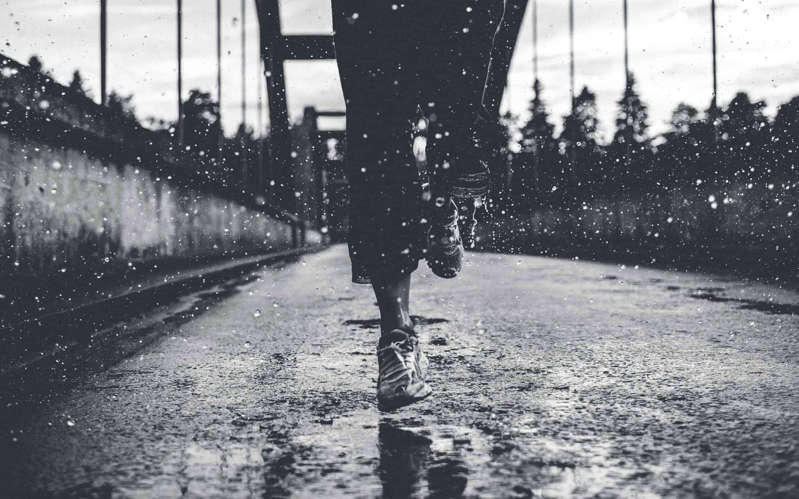 A woman running in the rain and water splashing up from the puddles.