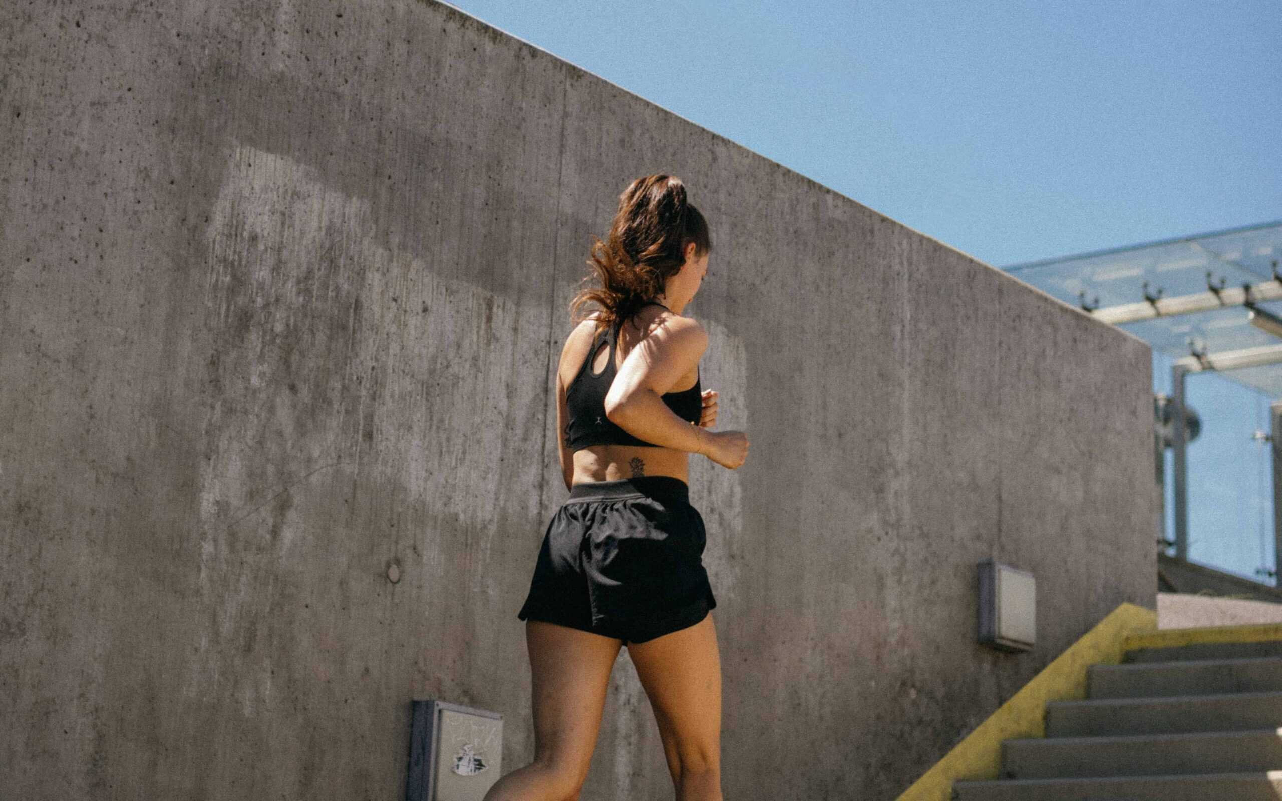 A woman running up stairs to perform hill repeats, one of the types of running.