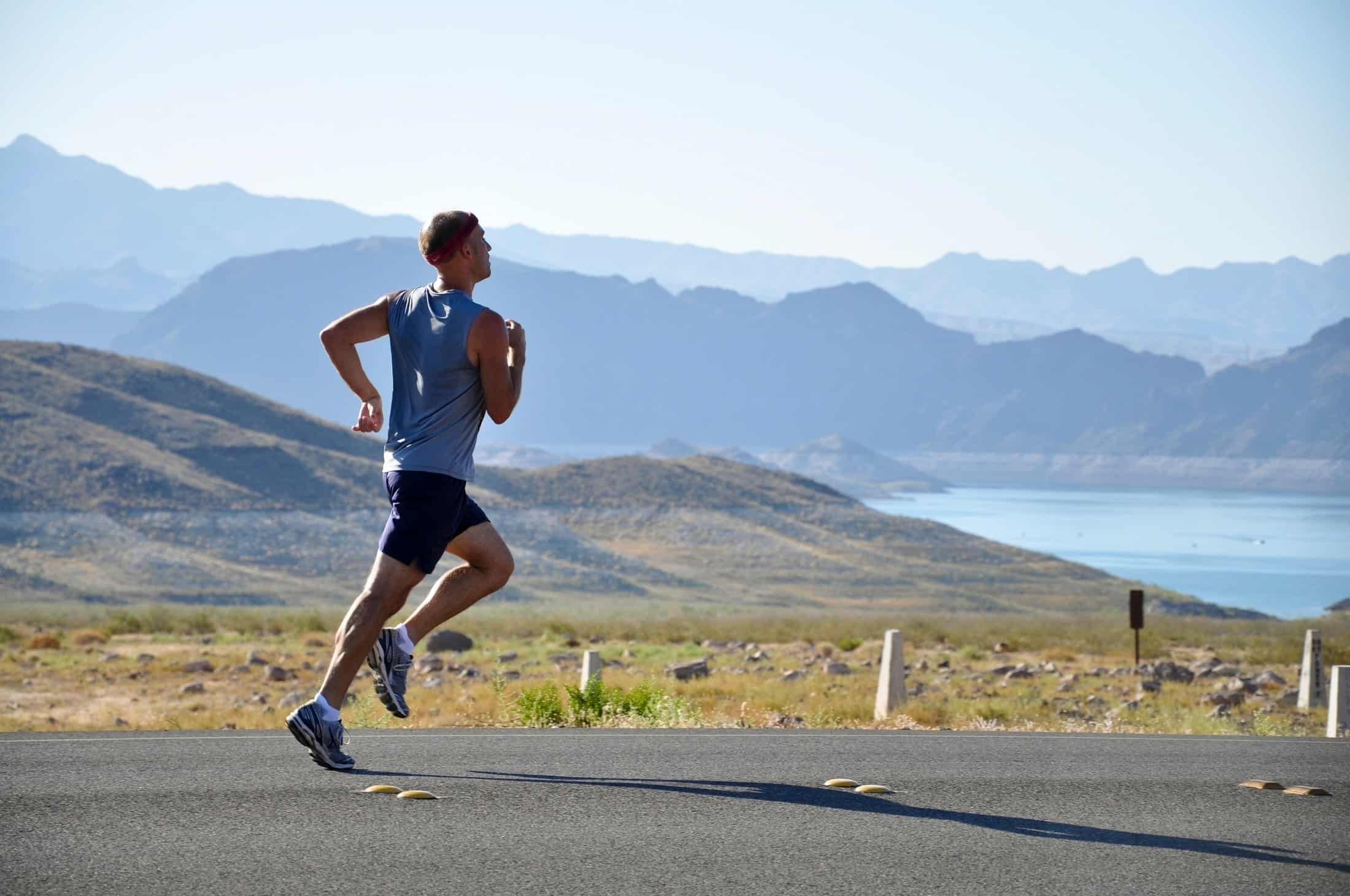 A male runner against a scenic backdrop doing a base run, one of the most common types of running.