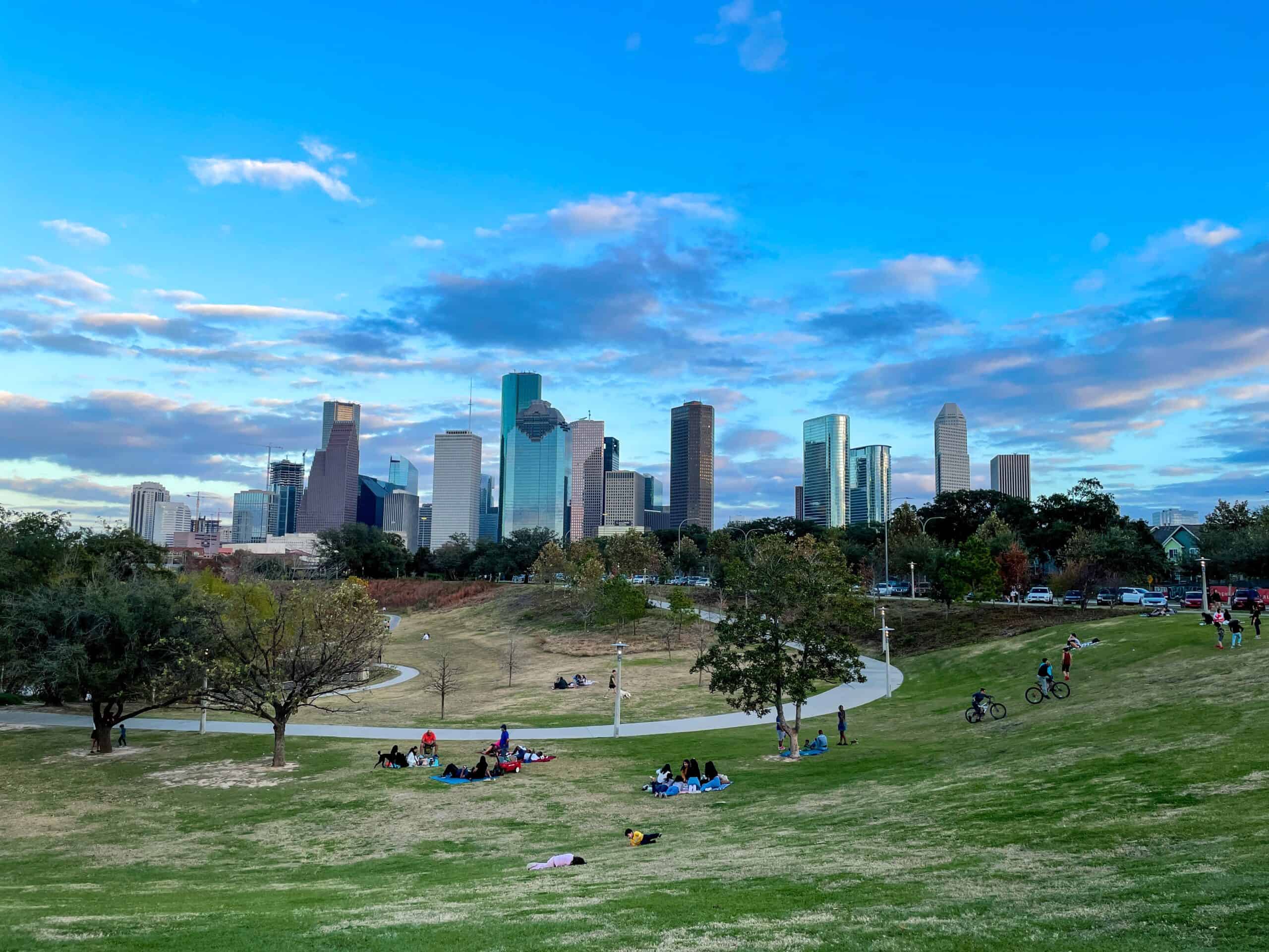 The Houston, Texas skyline with people picnicking and riding bikes and a park.