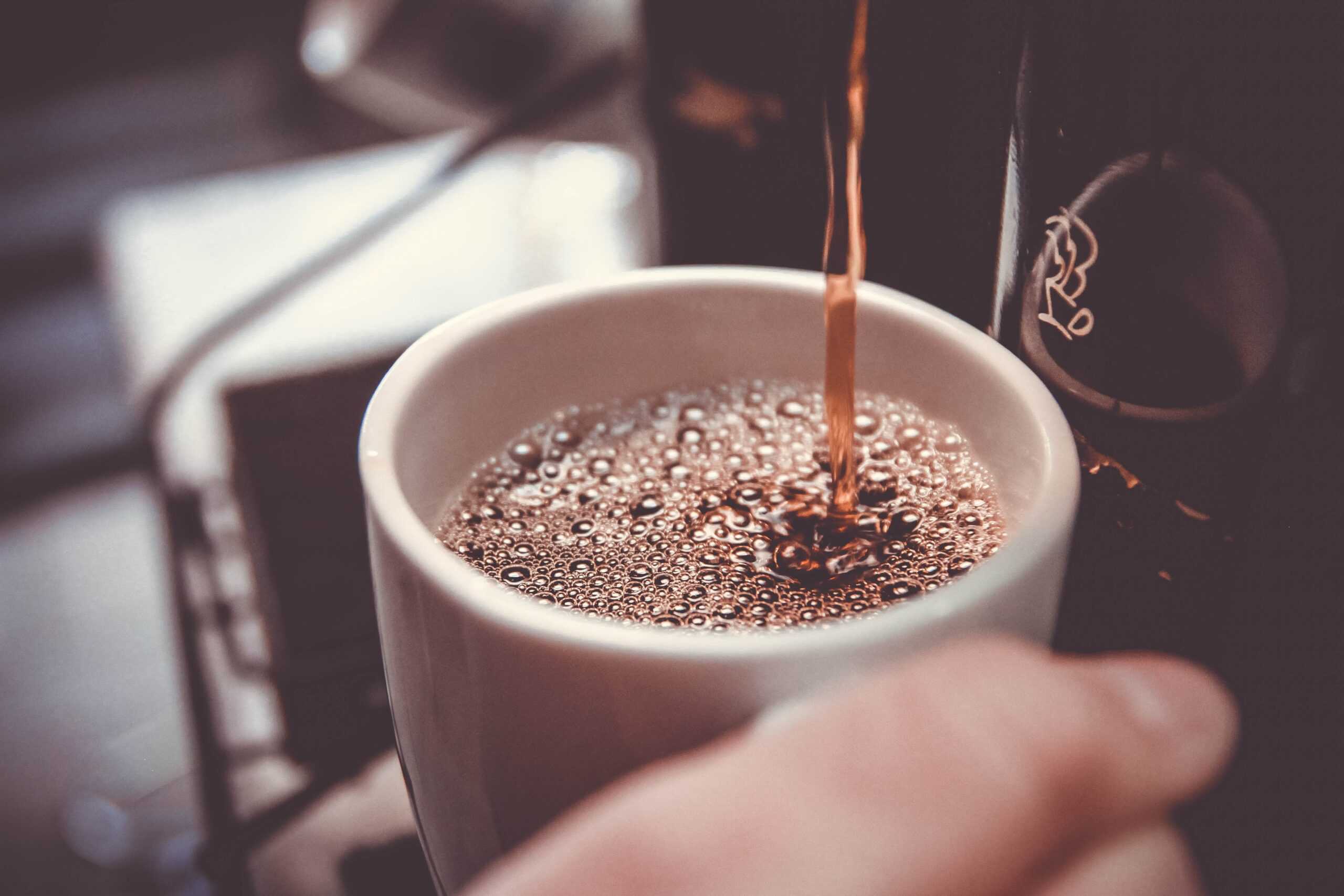 Drip coffee being poured into a coffee cup.
