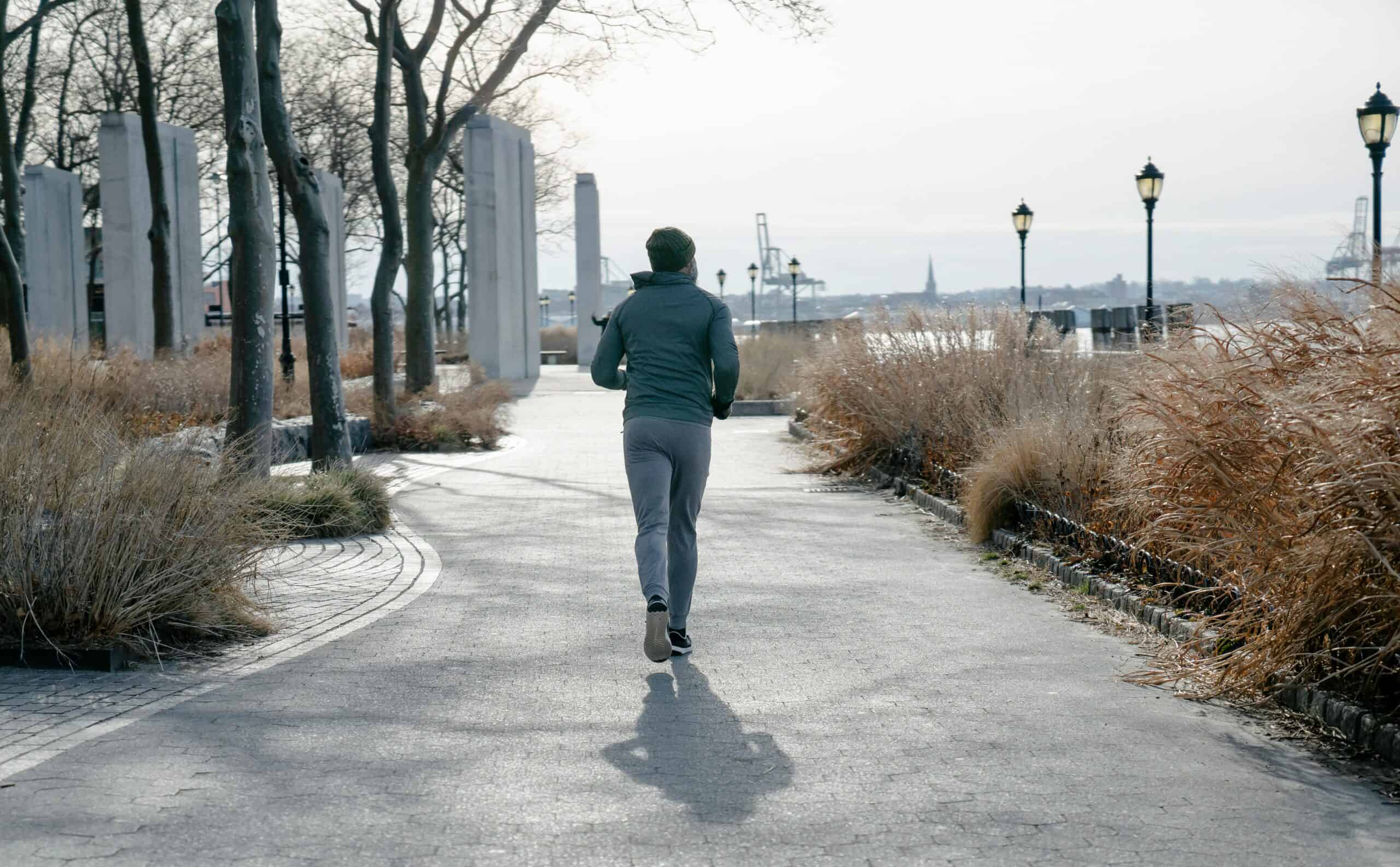 Man running in southern Manhattan with a sweatshirt and sweatpants as it's a cold weather course.