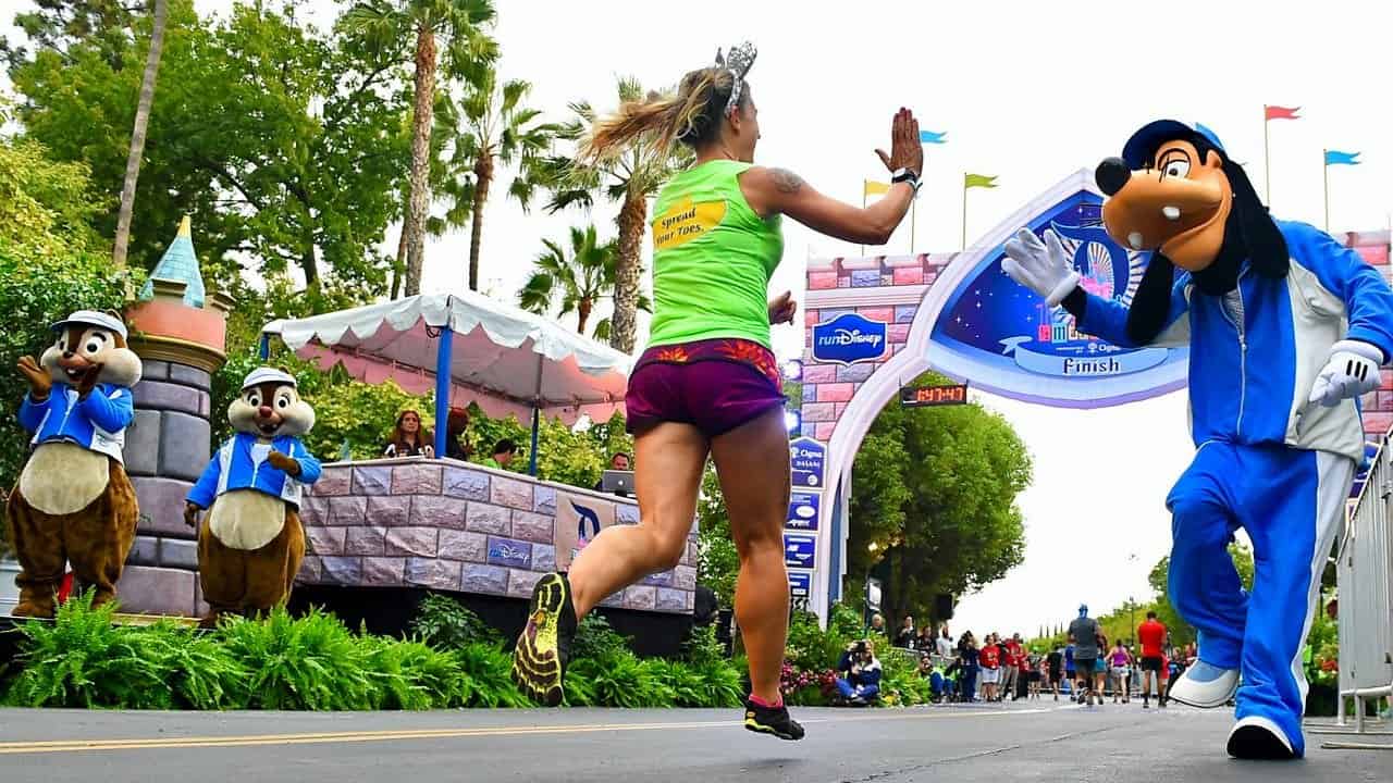 A girl running the Walt Disney World Half Marathon, giving Goofy a high five