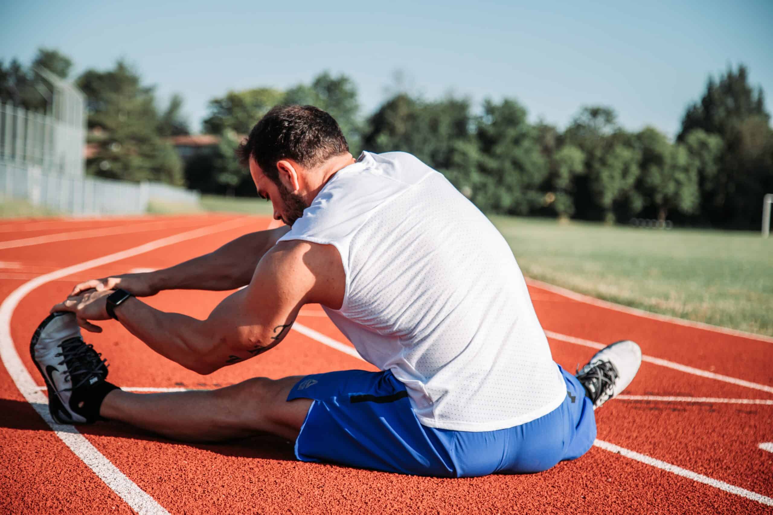 A runner on a track stretching for running recovery.