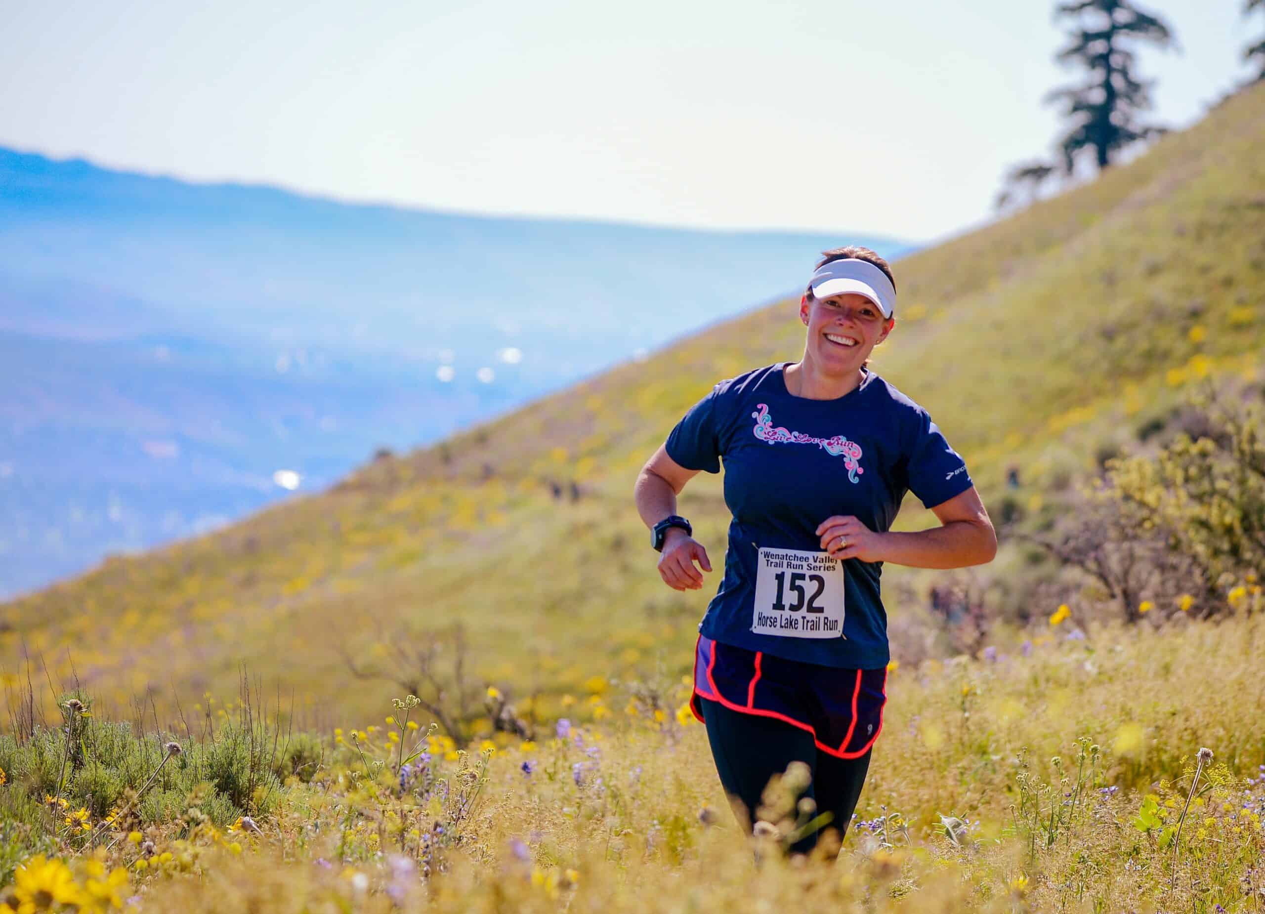 A woman at the Horse Lake Trail Run smiling on the trail. 