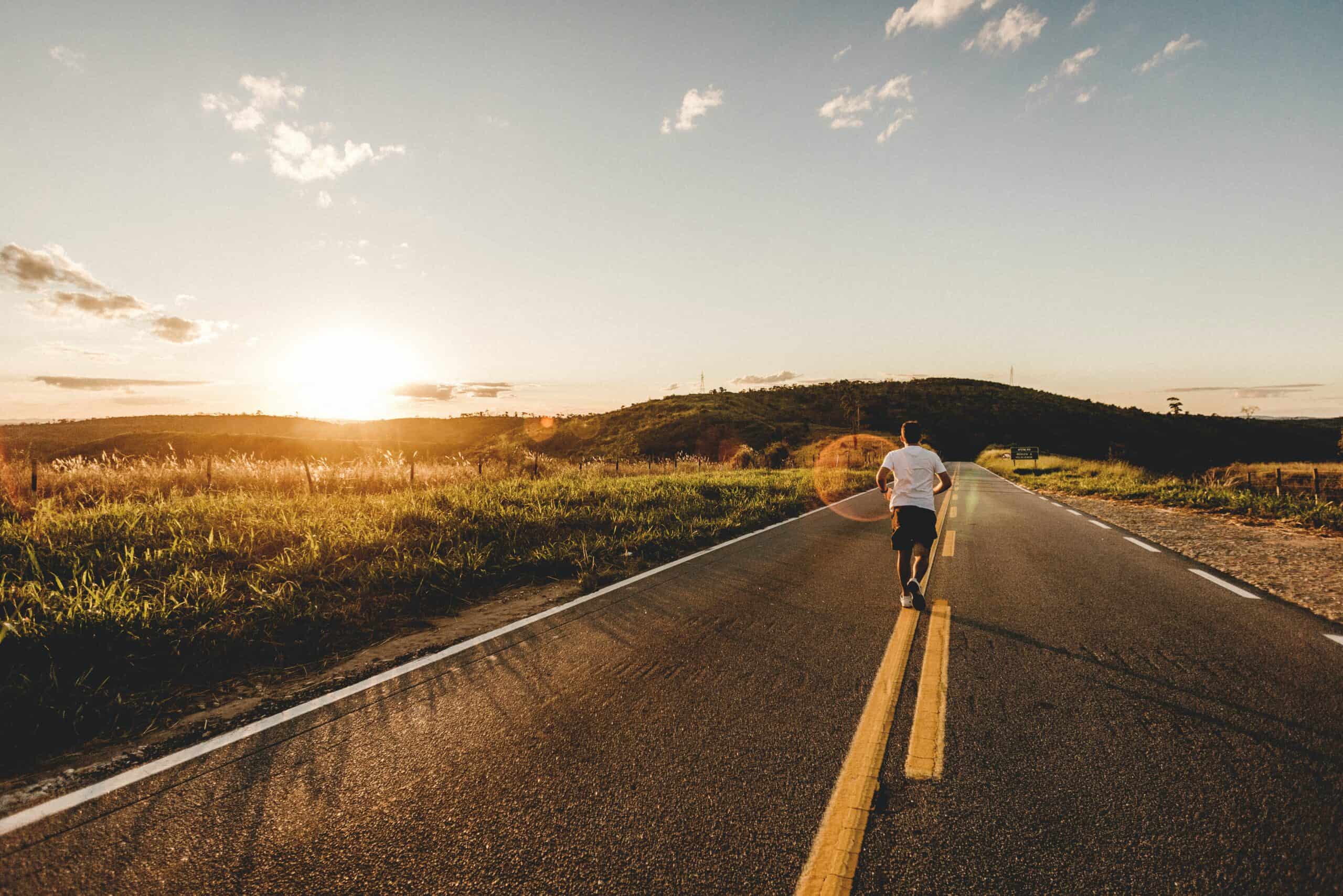 Man running on a road into the sunset on a rural background.