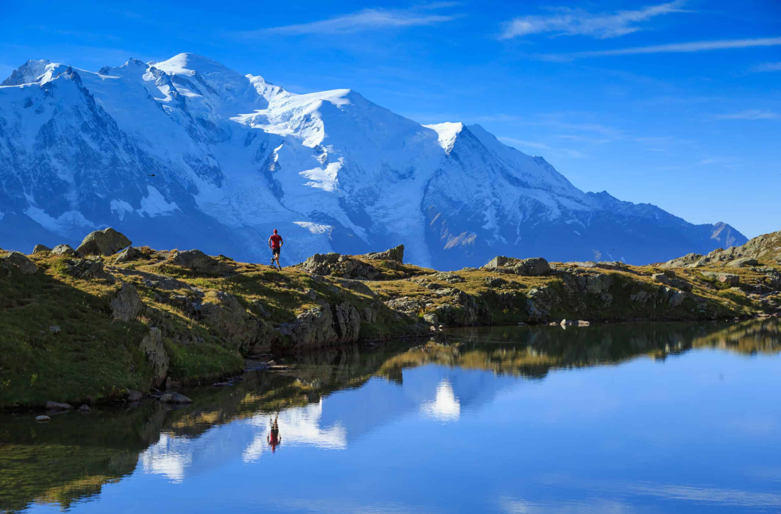 Athlete trail running at Lac De Chéserys, with the Mont Blanc in the background.