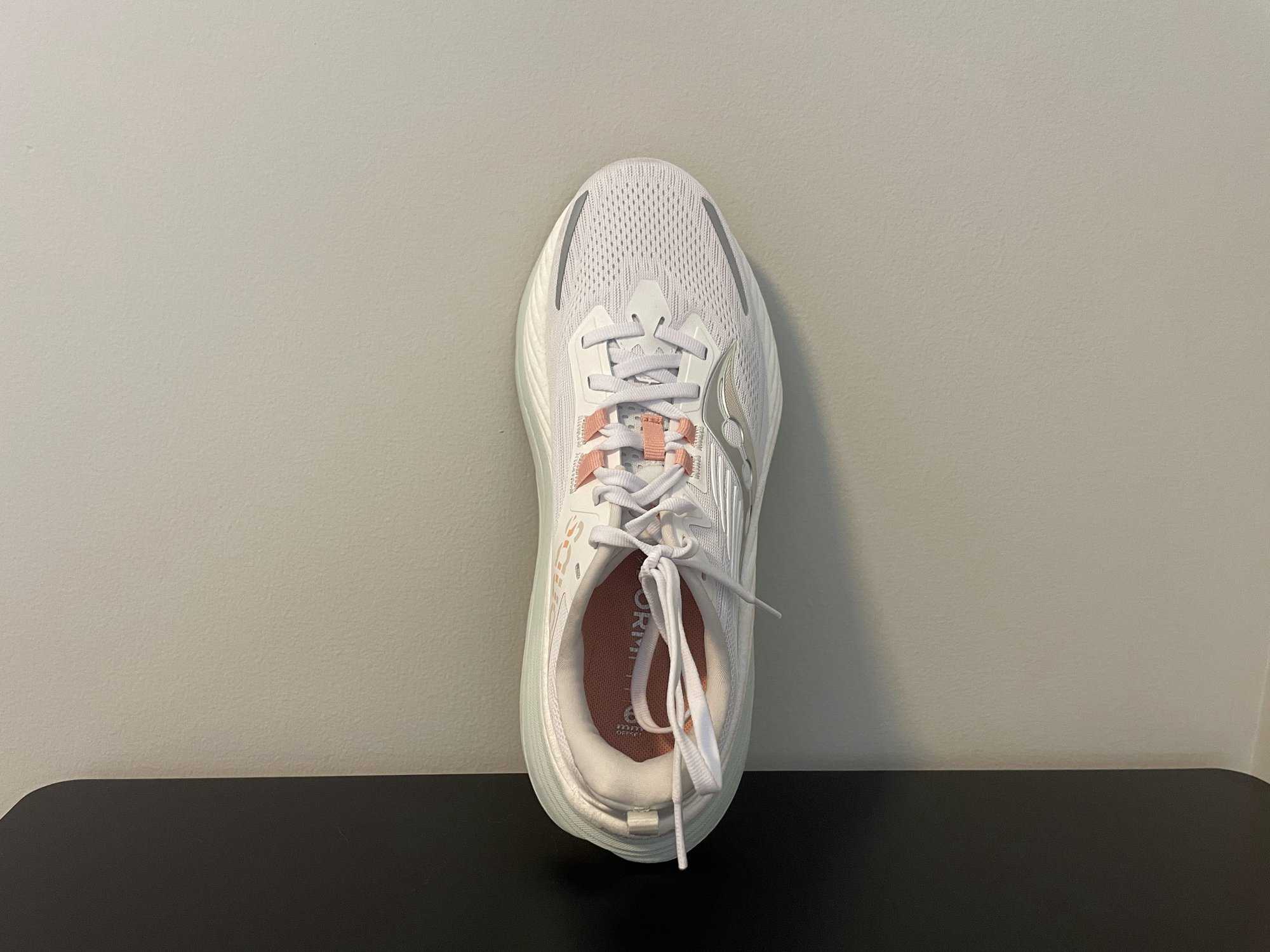 The Saucony Hurricane 24 leaning vertically against a wall, showing a top-down view of the running shoe