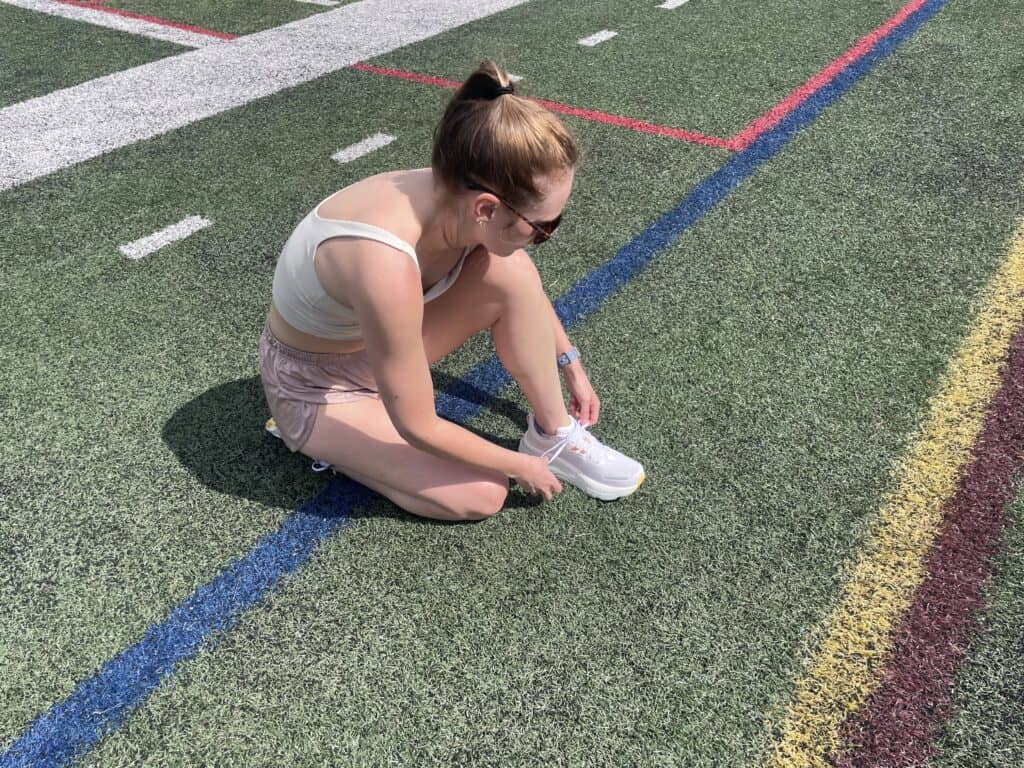 Writer Gabi Horndorp tying the Saucony Hurricane 24 on astroturf before a test run.
