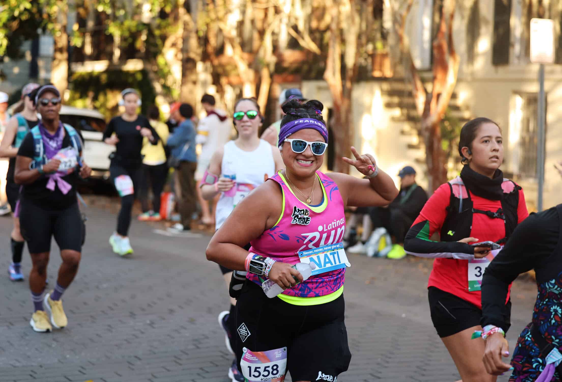 a runner holding up a peace sign in a colorful top at the every woman's marathon