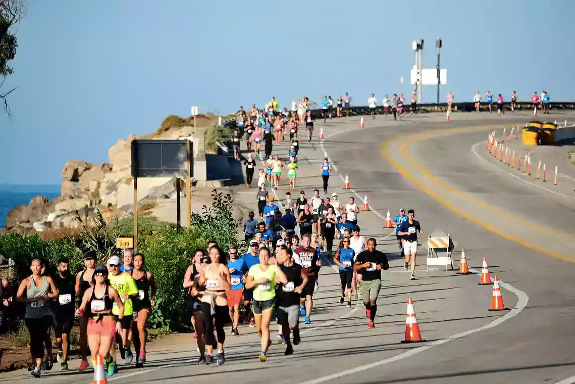A large group of runners participating in one of the most scenic half marathons on a winding coastal road.